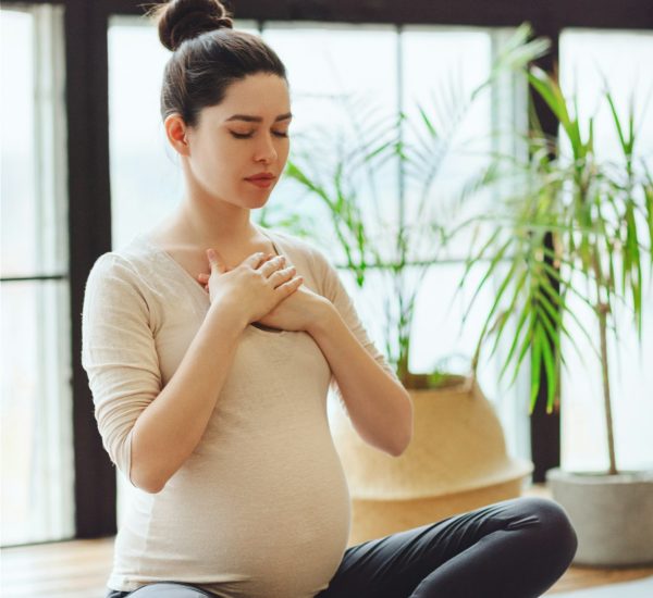 Meditation during pregnancy. Young calm tranquil pregnant woman doing yoga at home