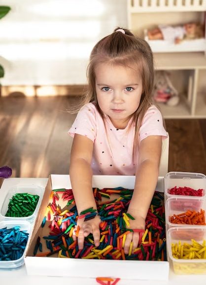 nina-pequena-jugando-contenedor-sensorial-pasta-tenida-colores-juego-sensorial-actividades-aprendiza