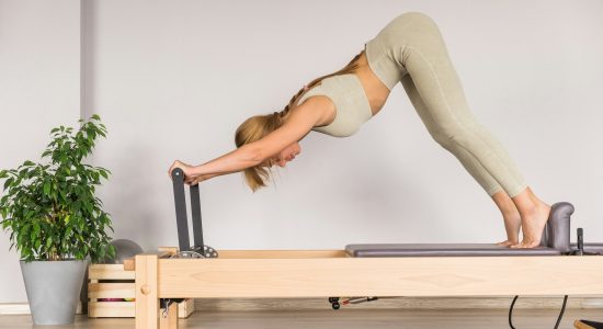 Woman training pilates on the reformer bed. Reformer pilates studio machine for fitness workouts in